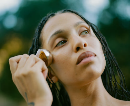 Woman applying makeup with a brush outdoors